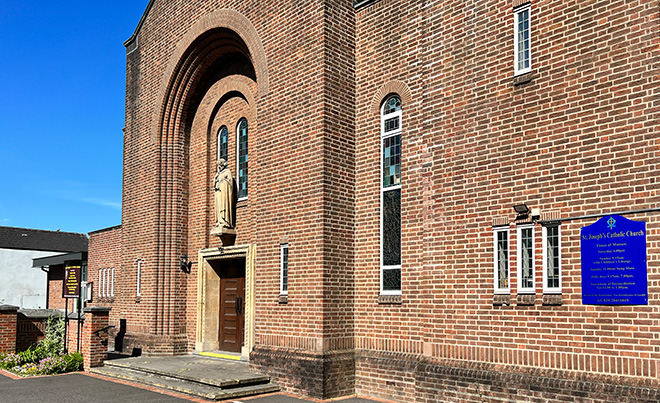 The church from the front, showing the 1930s brickwork and the statue of Saint Joseph.
